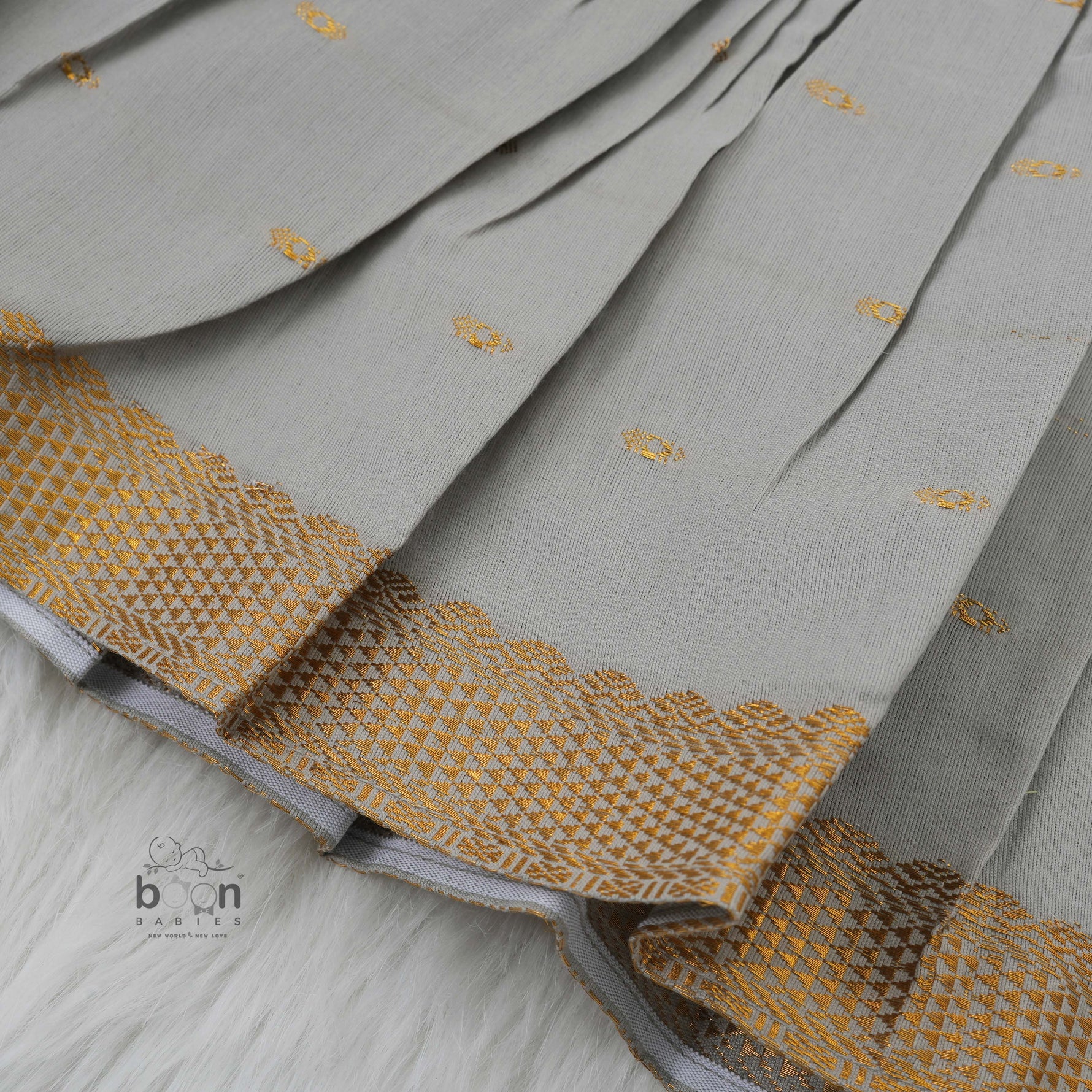 Festive grey silk Onam knot frock with triangle yoke design & zari border. Perfect for baby girls (0–12M).