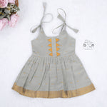 Festive grey silk Onam knot frock with triangle yoke design & zari border. Perfect for baby girls (0–12M).