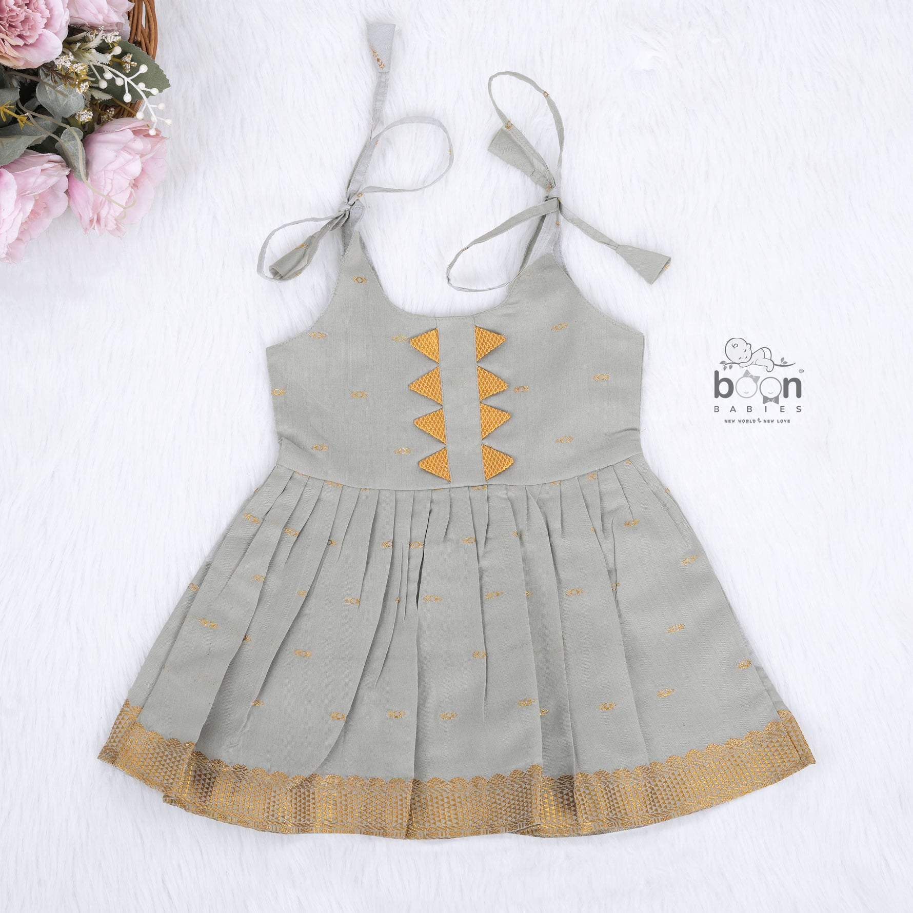 Festive grey silk Onam knot frock with triangle yoke design & zari border. Perfect for baby girls (0–12M).