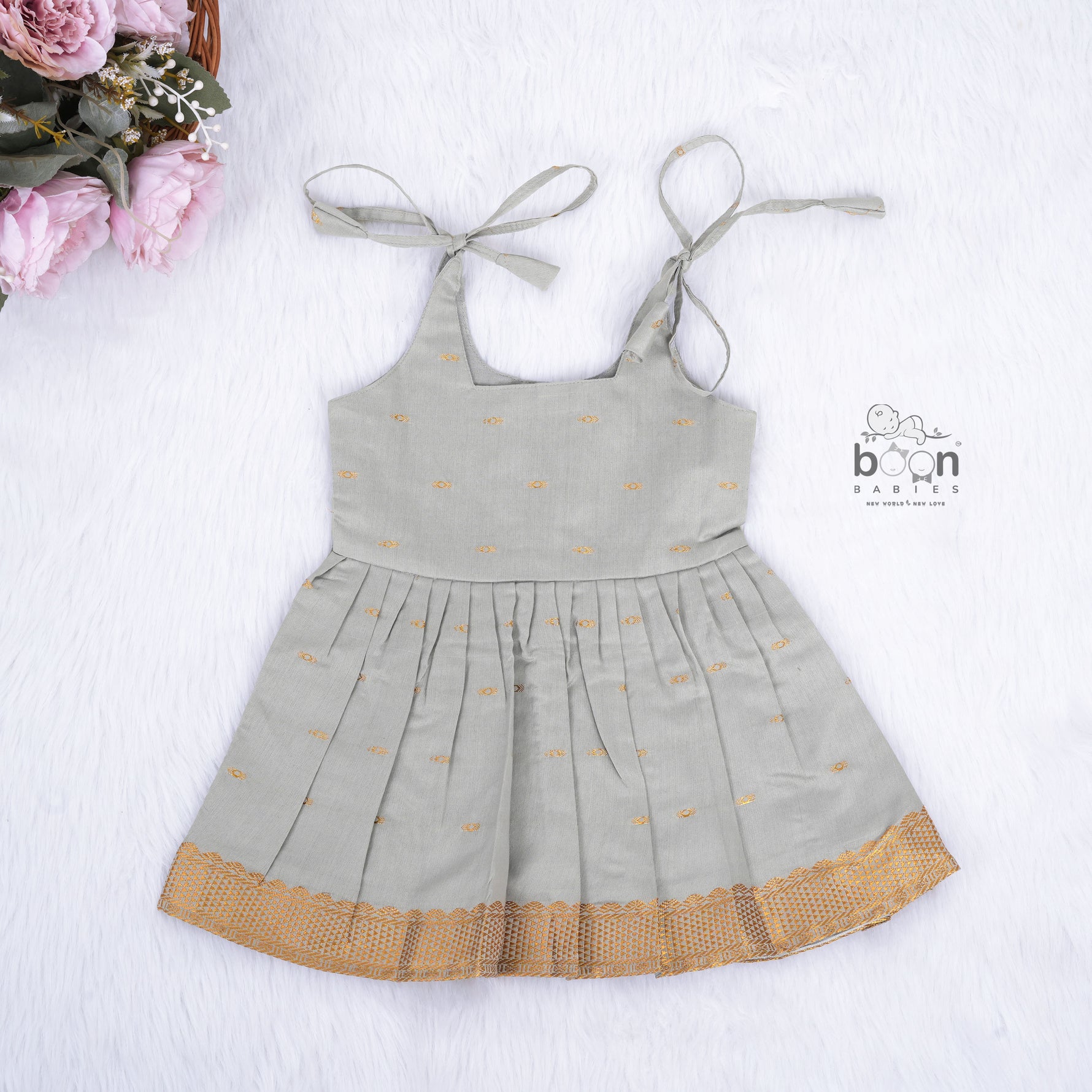 Festive grey silk Onam knot frock with triangle yoke design & zari border. Perfect for baby girls (0–12M).