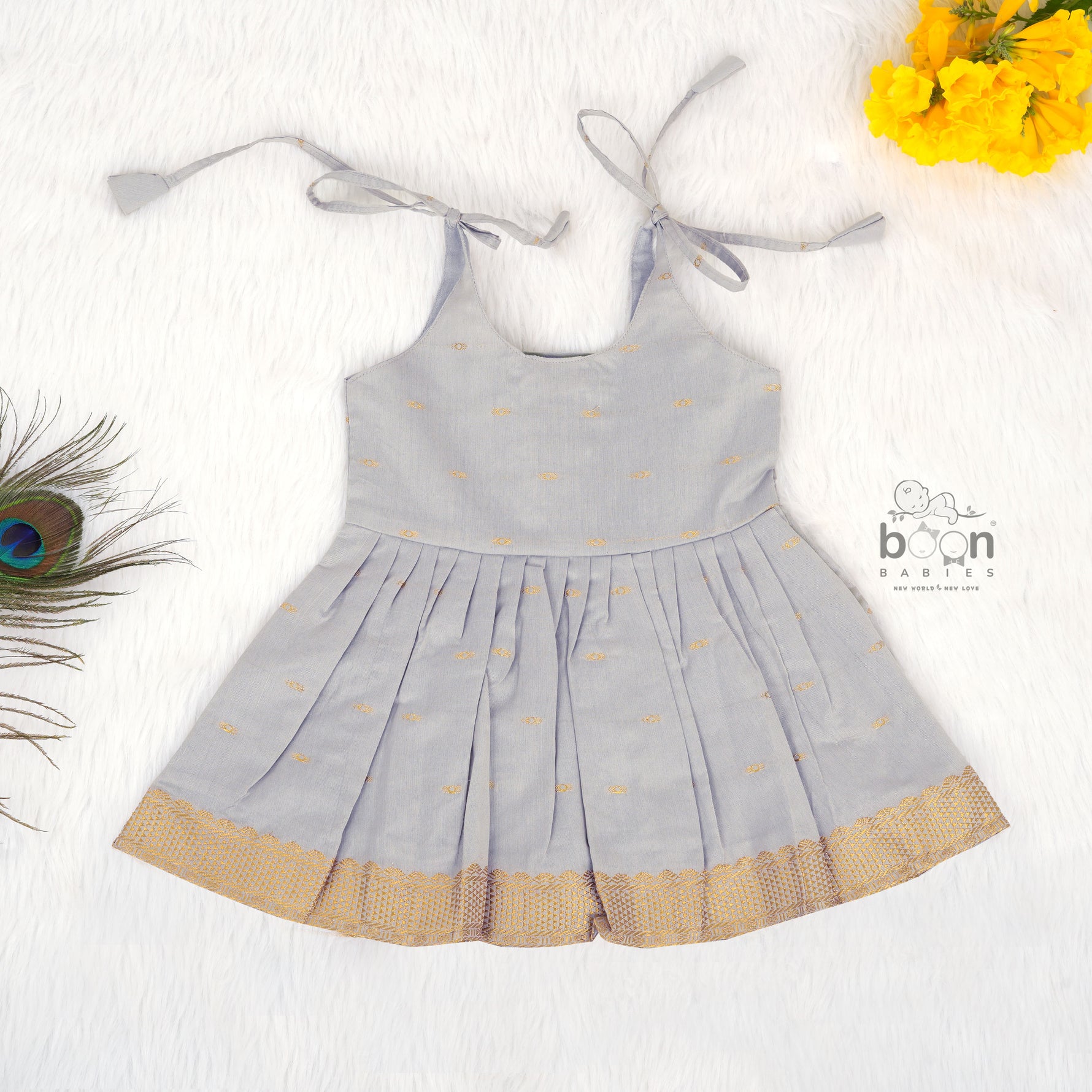 Grey silk knot frock with zari border & pleated design for baby girls (0–12 months). Stylish, festive & comfortable.
