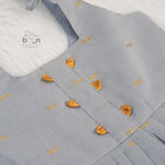 Grey silk knot frock with zari border & pleated design for baby girls (0–12 months). Stylish, festive & comfortable.
