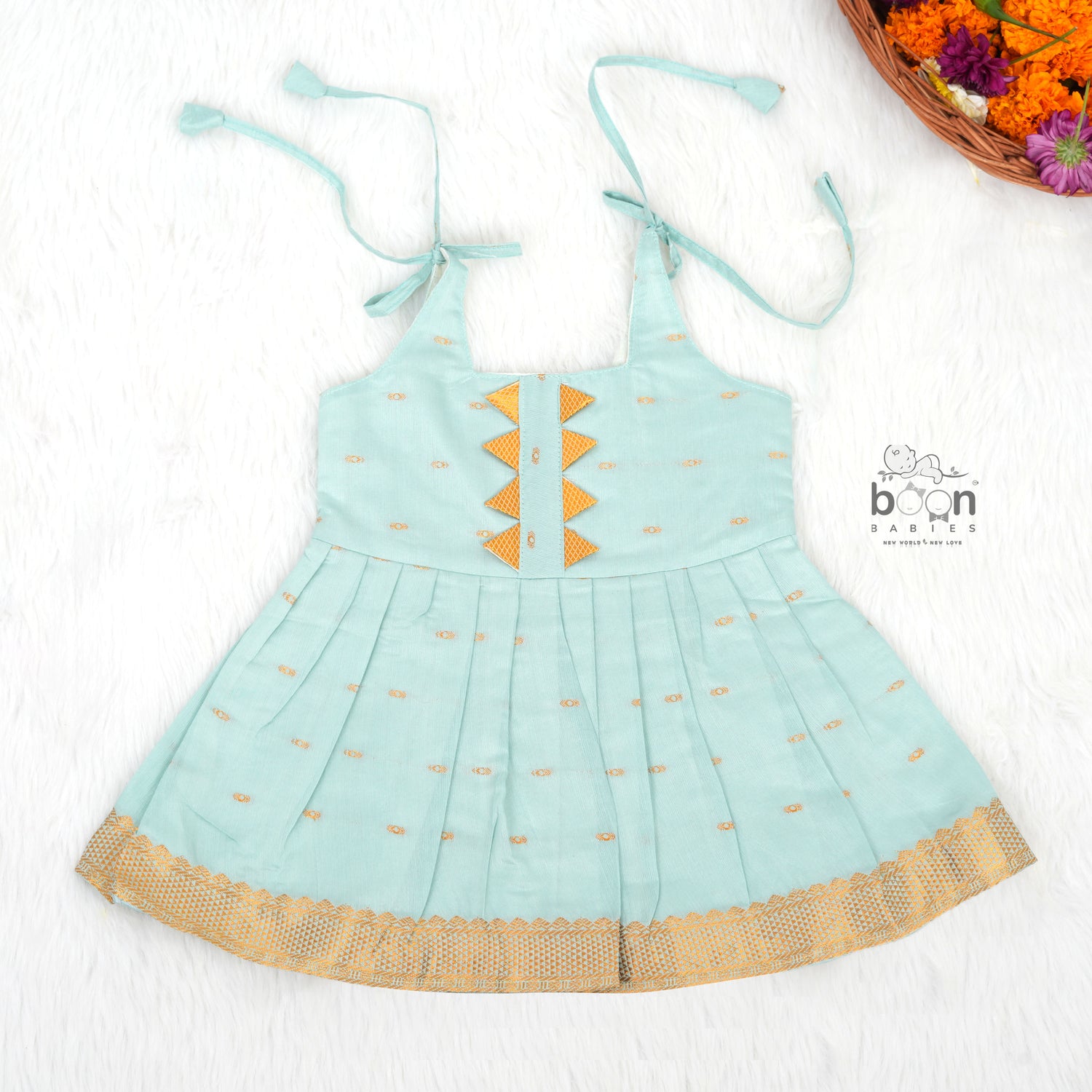 Mint green silk Onam knot frock with triangle yoke, zari border & knot straps. Ideal festive outfit for baby girls (0–12M).