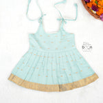 Mint green silk Onam knot frock with triangle yoke, zari border & knot straps. Ideal festive outfit for baby girls (0–12M).