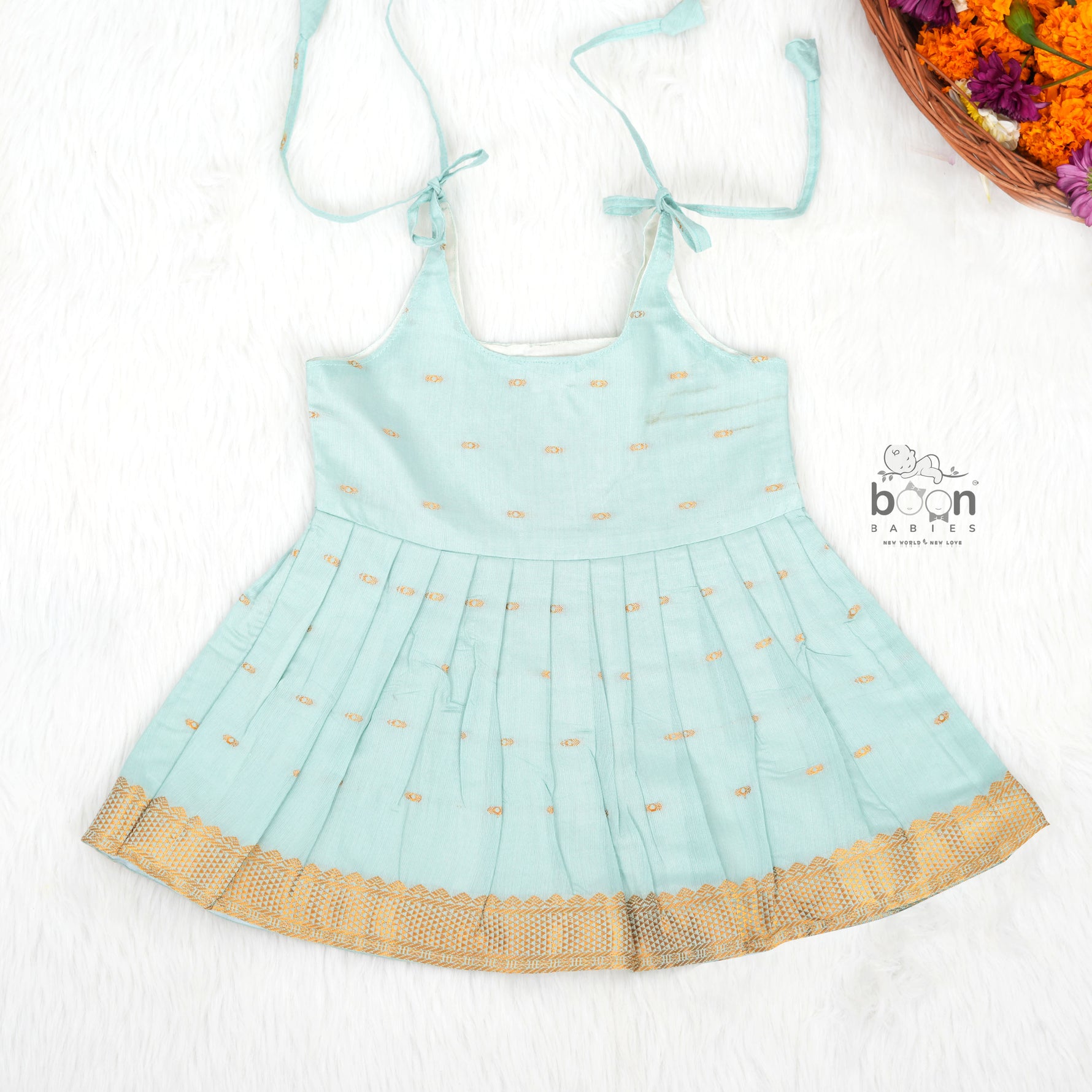 Mint green silk Onam knot frock with triangle yoke, zari border & knot straps. Ideal festive outfit for baby girls (0–12M).