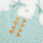 Mint green silk Onam knot frock with triangle yoke, zari border & knot straps. Ideal festive outfit for baby girls (0–12M).