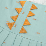 Mint green silk Onam knot frock with triangle yoke, zari border & knot straps. Ideal festive outfit for baby girls (0–12M).