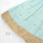 Mint green silk Onam knot frock with triangle yoke, zari border & knot straps. Ideal festive outfit for baby girls (0–12M).