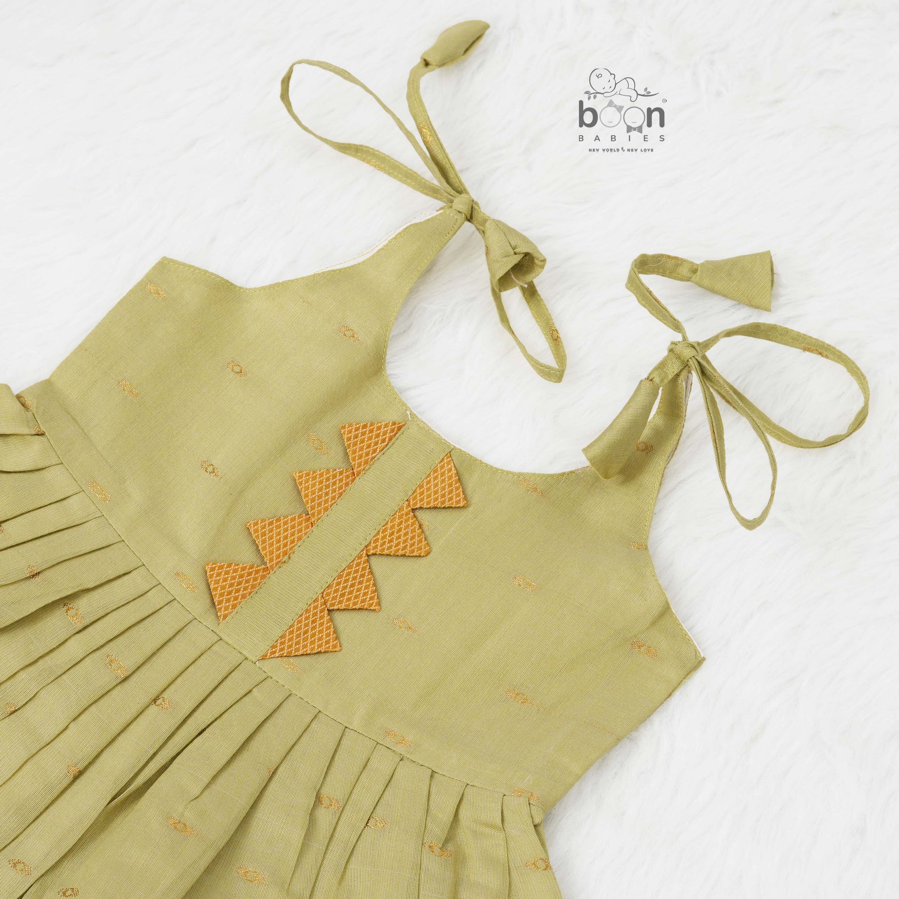 Olive green silk Onam knot frock with zari border & triangle yoke. Ages 0–12M. Perfect festive outfit for baby girls.