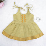 Olive green silk Onam knot frock with zari border & triangle yoke. Ages 0–12M. Perfect festive outfit for baby girls.