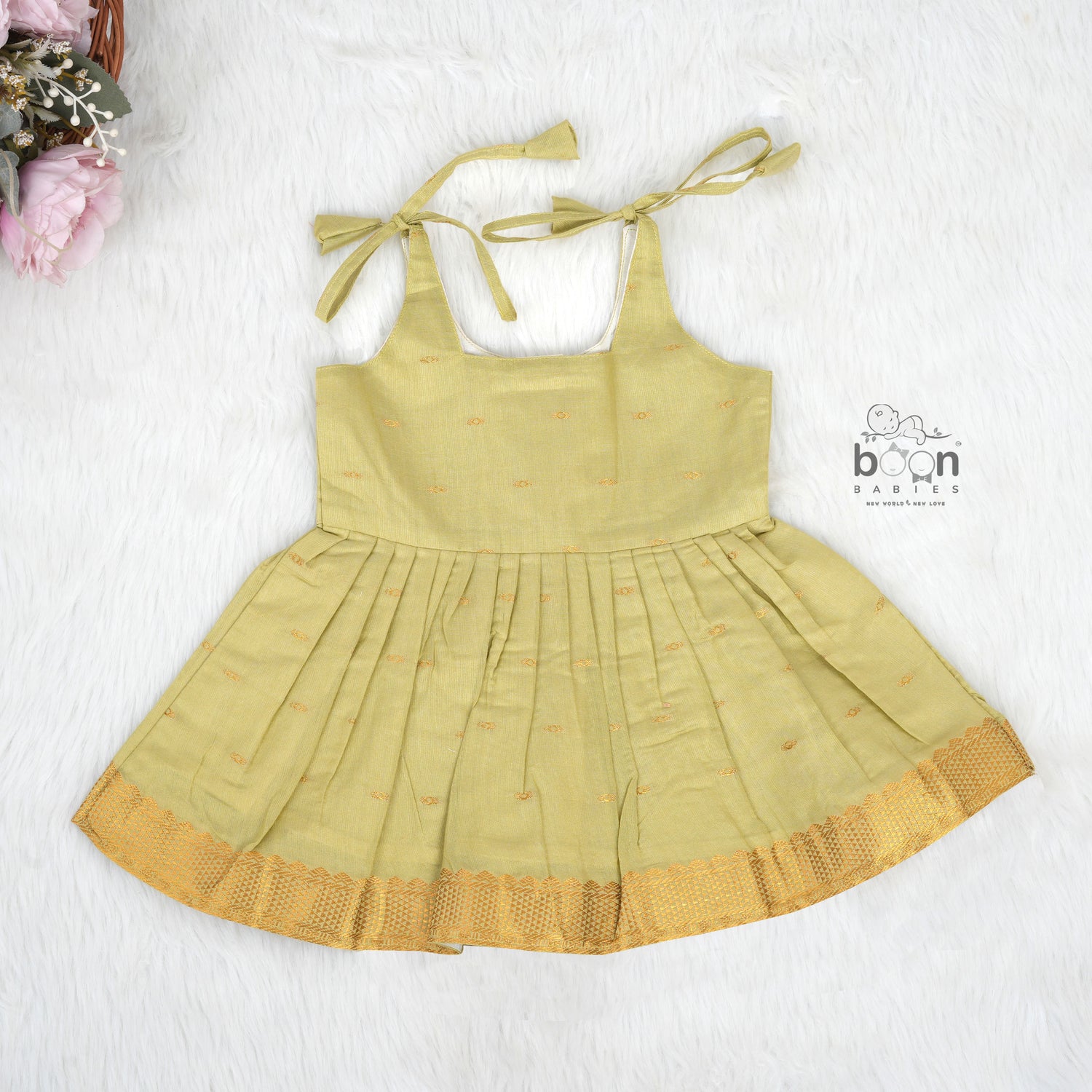Olive green silk Onam knot frock with zari border & triangle yoke. Ages 0–12M. Perfect festive outfit for baby girls.