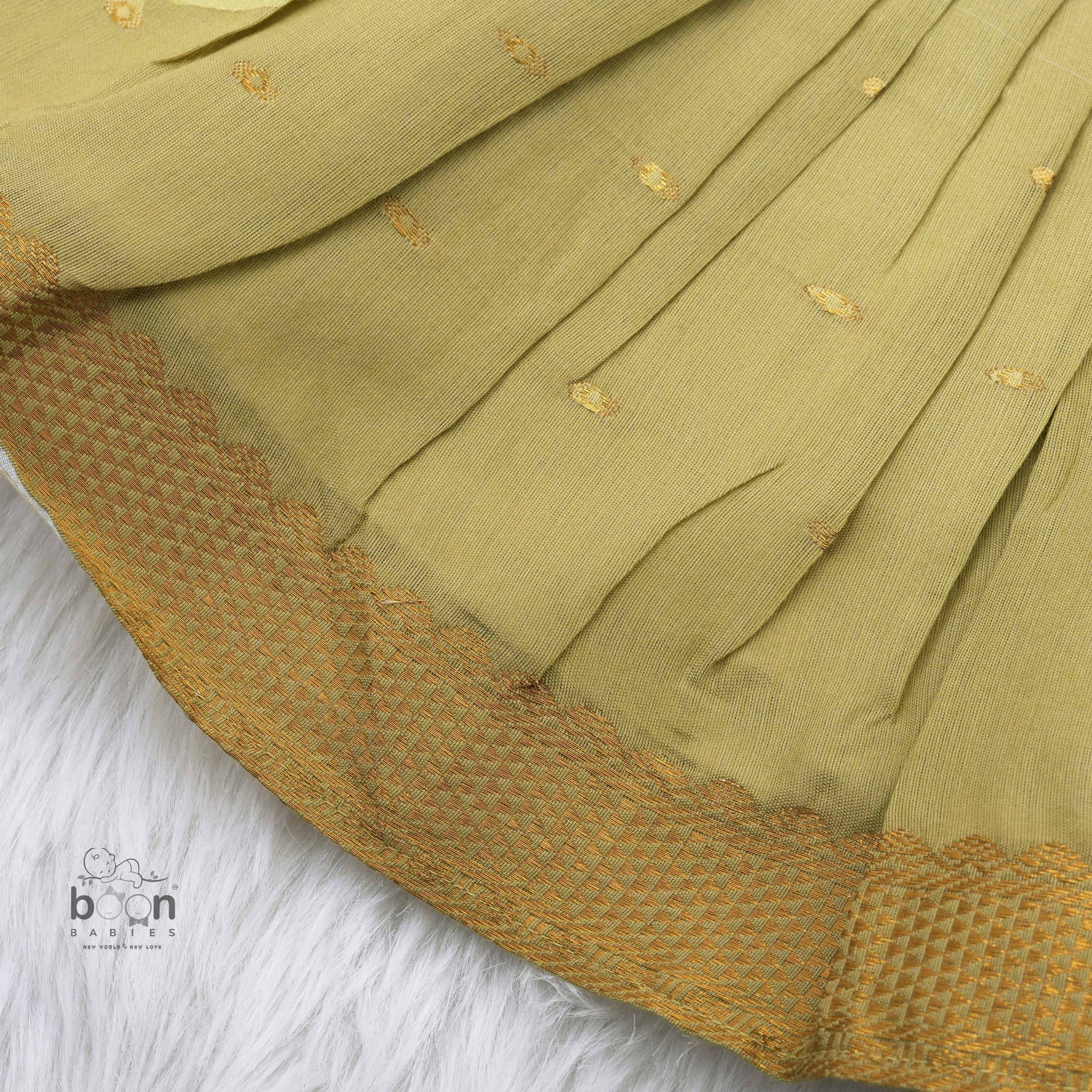 Olive green silk Onam knot frock with zari border & triangle yoke. Ages 0–12M. Perfect festive outfit for baby girls.