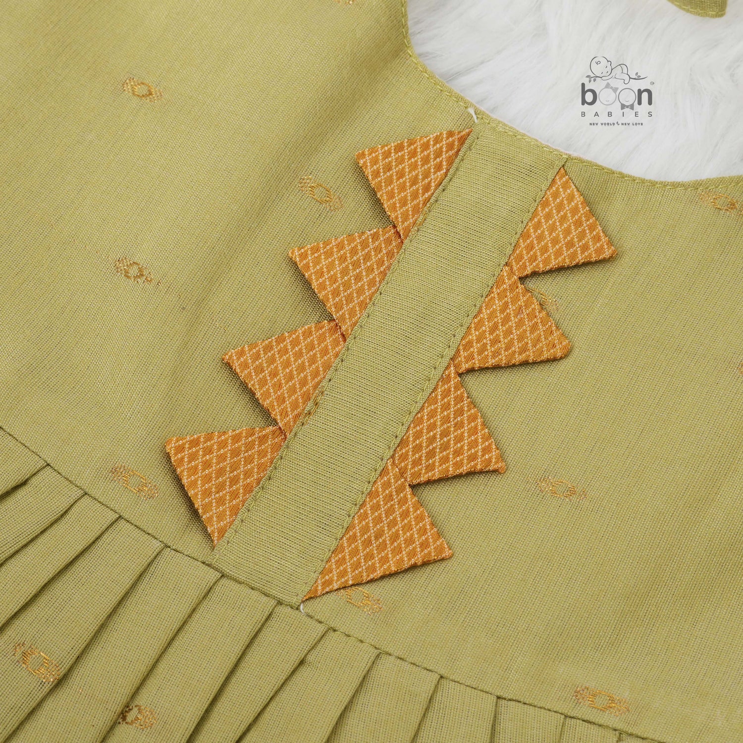 Olive green silk Onam knot frock with zari border & triangle yoke. Ages 0–12M. Perfect festive outfit for baby girls.