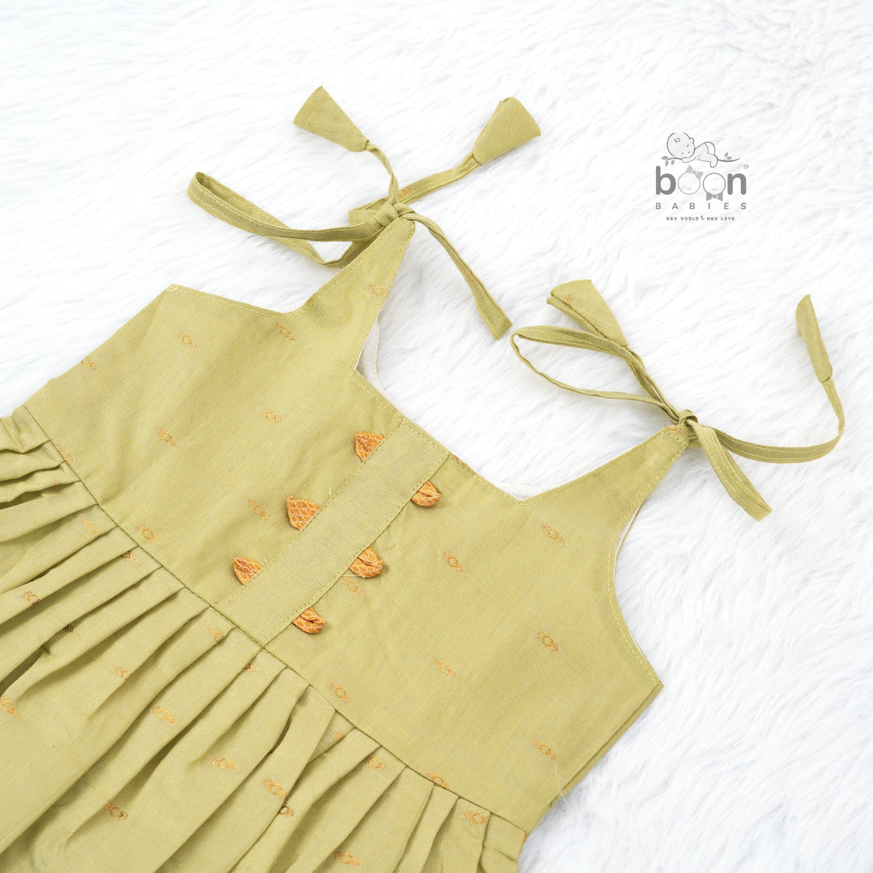 Olive green silk knot frock with zari border for baby girls (0–12 months). Festive, elegant & comfortable for Onam celebrations.

