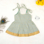 Festive silk knot frock for baby girls (6–12 months) with zari border & tie-up straps. Perfect for Onam & traditional celebrations.
