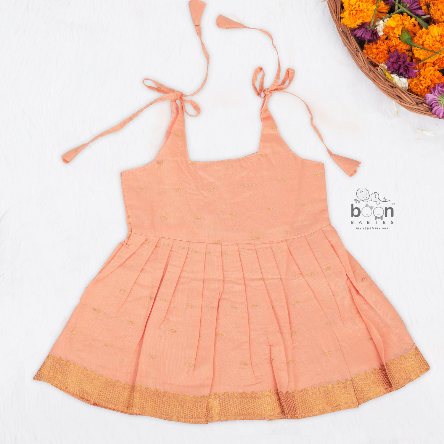 Peach silk Onam knot frock with zari border & triangle yoke. Ages 0–12M. Elegant festive outfit for baby girls.