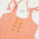 Peach silk Onam knot frock with zari border & triangle yoke. Ages 0–12M. Elegant festive outfit for baby girls.