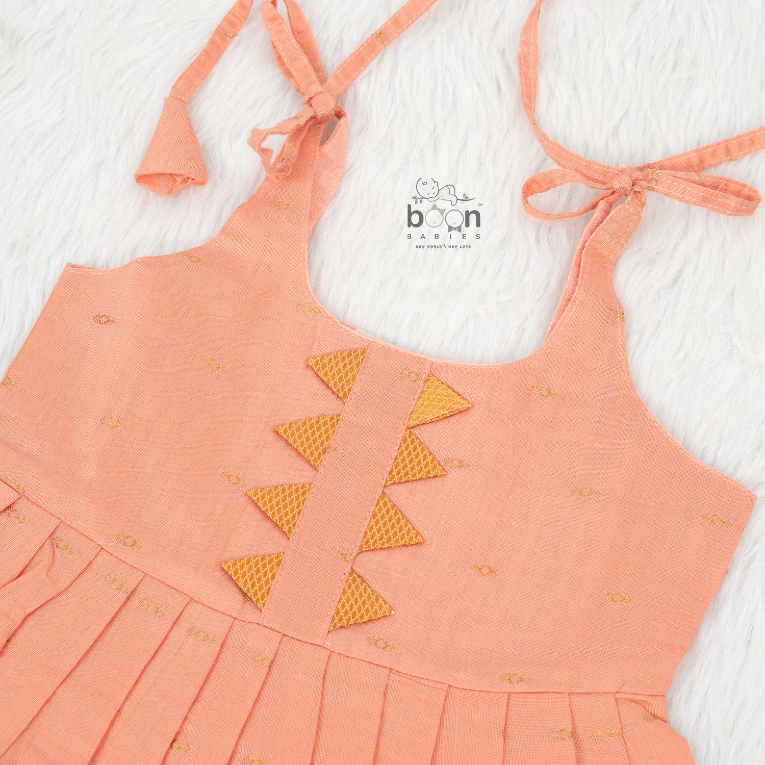 Peach silk Onam knot frock with zari border & triangle yoke. Ages 0–12M. Elegant festive outfit for baby girls.