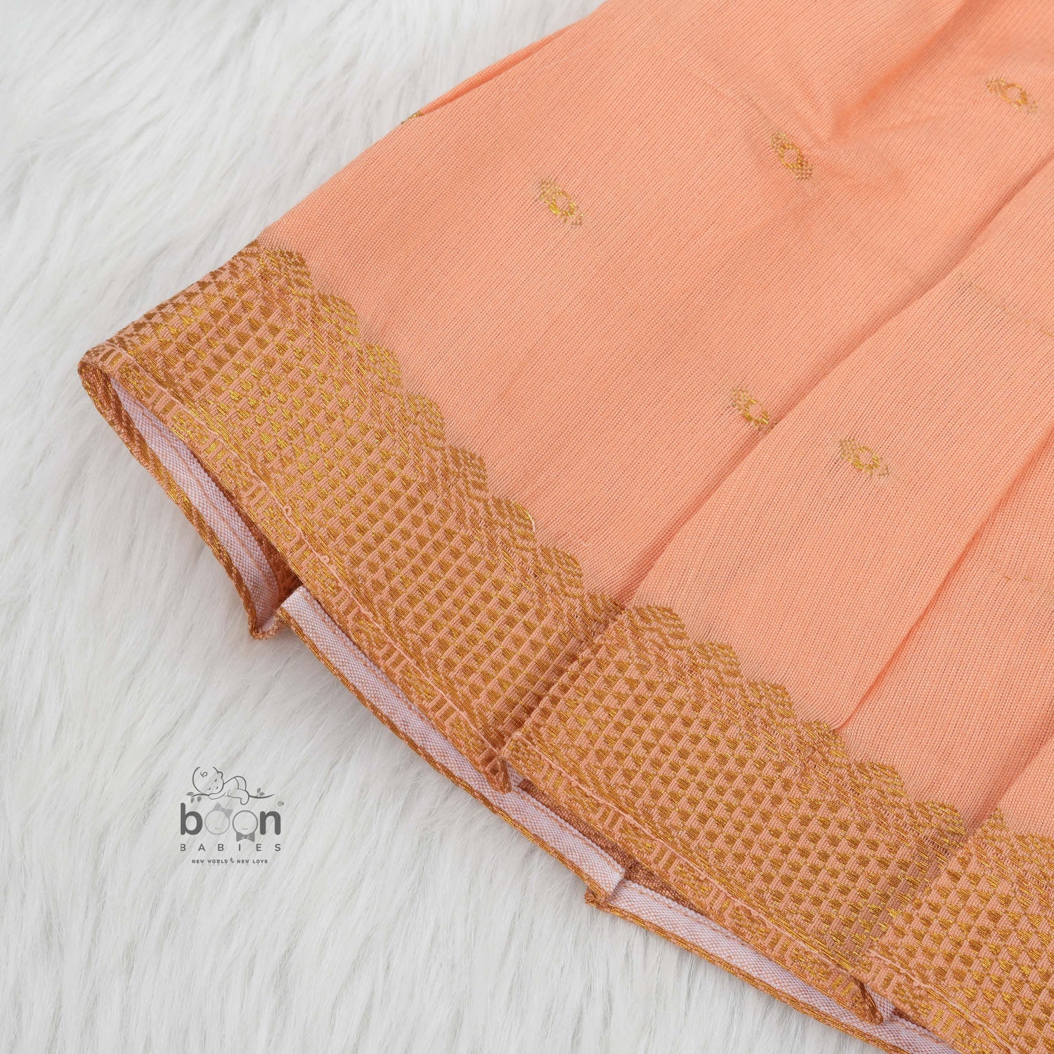 Peach silk Onam knot frock with zari border & triangle yoke. Ages 0–12M. Elegant festive outfit for baby girls.