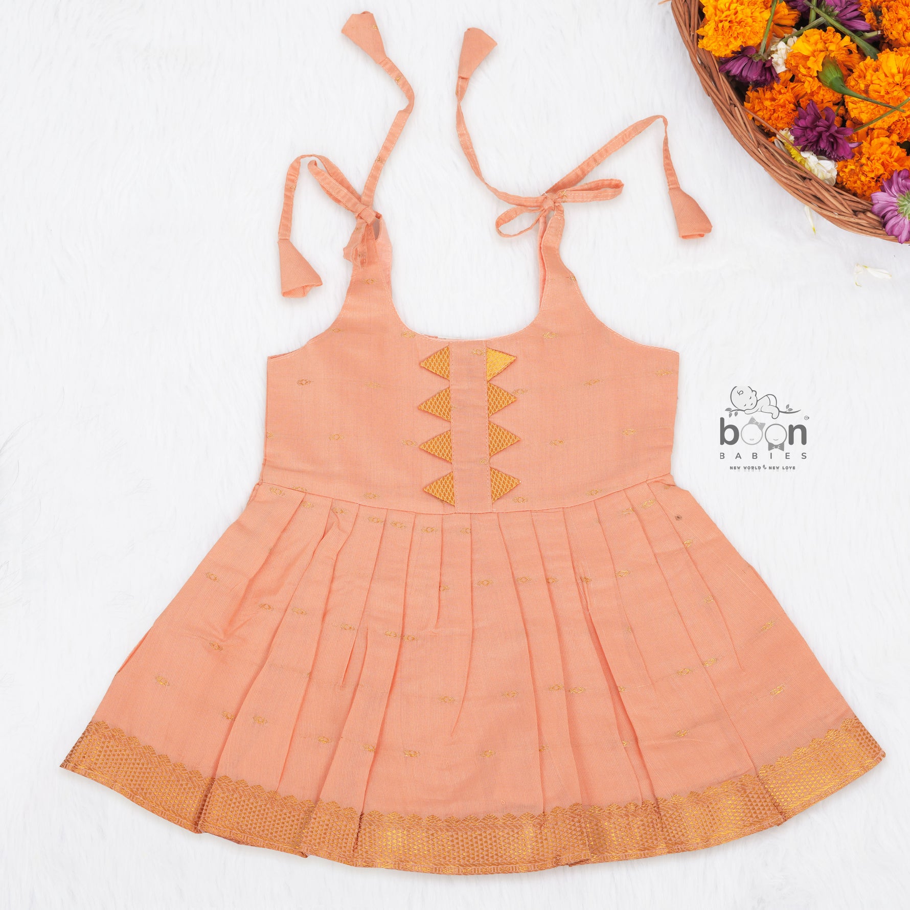 Peach silk Onam knot frock with zari border & triangle yoke. Ages 0–12M. Elegant festive outfit for baby girls.
