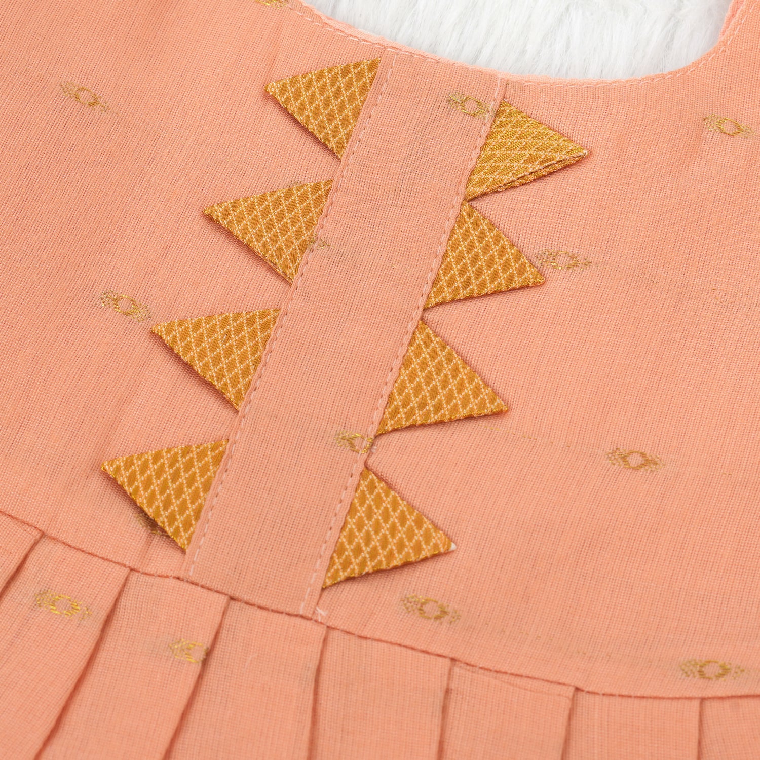 Peach silk Onam knot frock with zari border & triangle yoke. Ages 0–12M. Elegant festive outfit for baby girls.