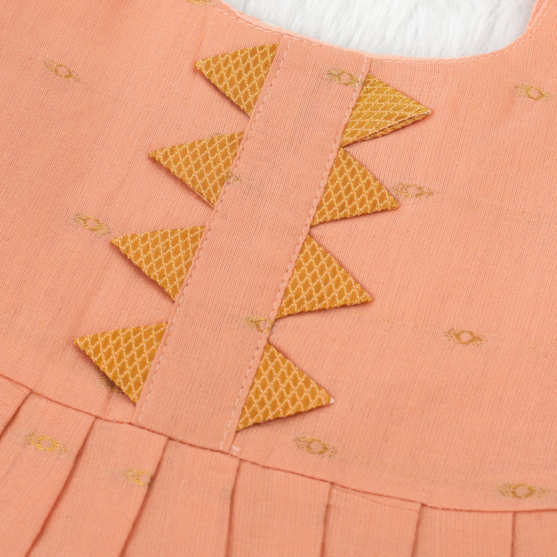 Peach silk Onam knot frock with zari border & triangle yoke. Ages 0–12M. Elegant festive outfit for baby girls.