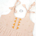 Beige silk Onam knot frock with zari border & triangle yoke. Ages 0–12M. Elegant festive outfit for baby girls.