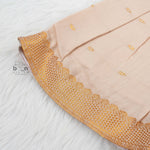 Beige silk Onam knot frock with zari border & triangle yoke. Ages 0–12M. Elegant festive outfit for baby girls.