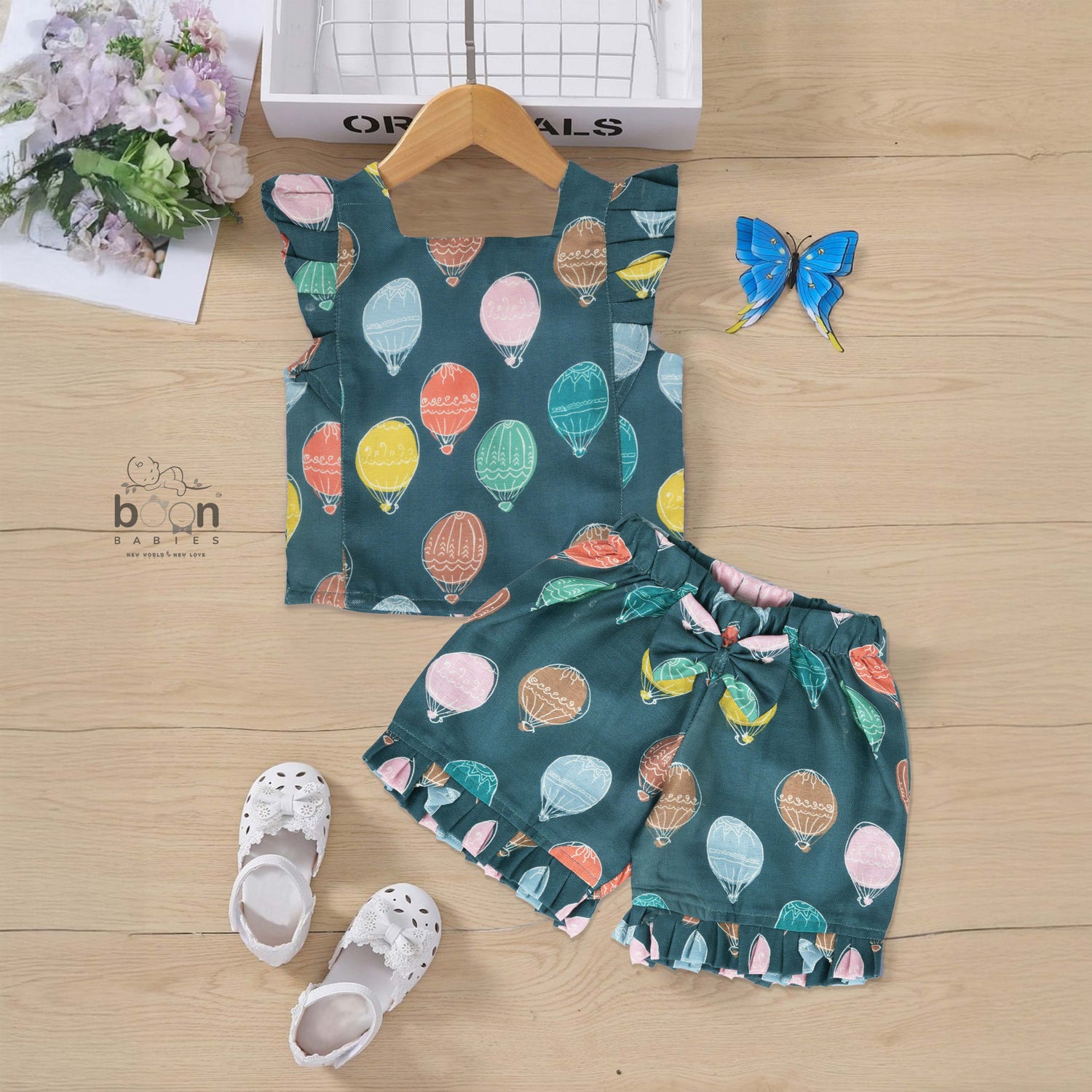 Cotton frill top & shorts set with teal base and multicolor hot air balloon print. Sizes 6M–5Y. Cute, comfy & playful casual wear for girls.
