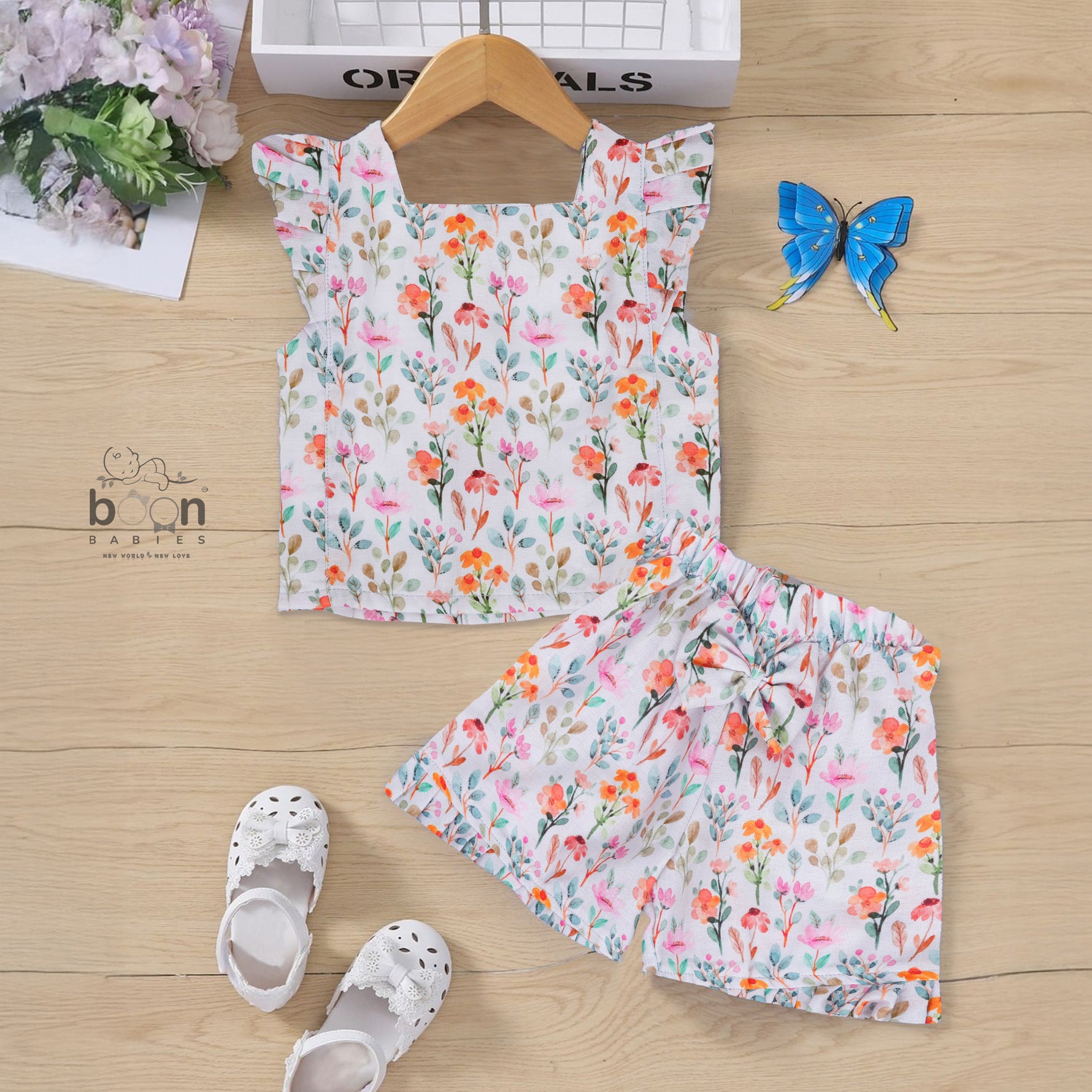 White cotton frill top with floral shorts. Ages 6M–5Y. Lightweight & stylish summer outfit for baby girls.
