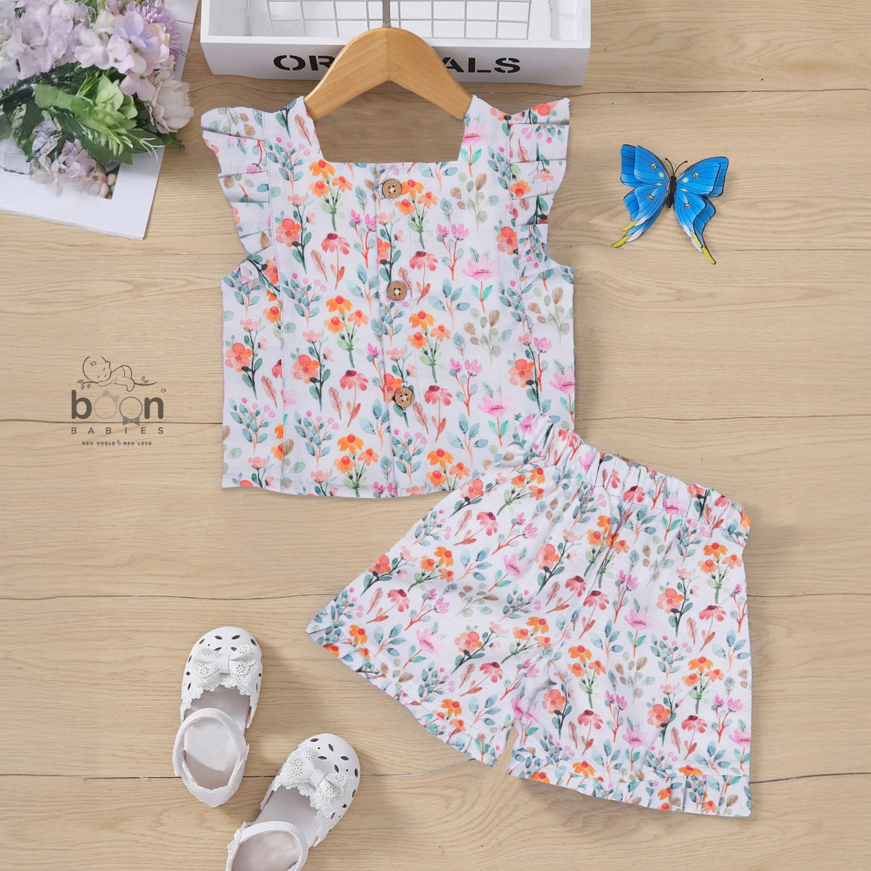 White cotton frill top with floral shorts. Ages 6M–5Y. Lightweight & stylish summer outfit for baby girls.
