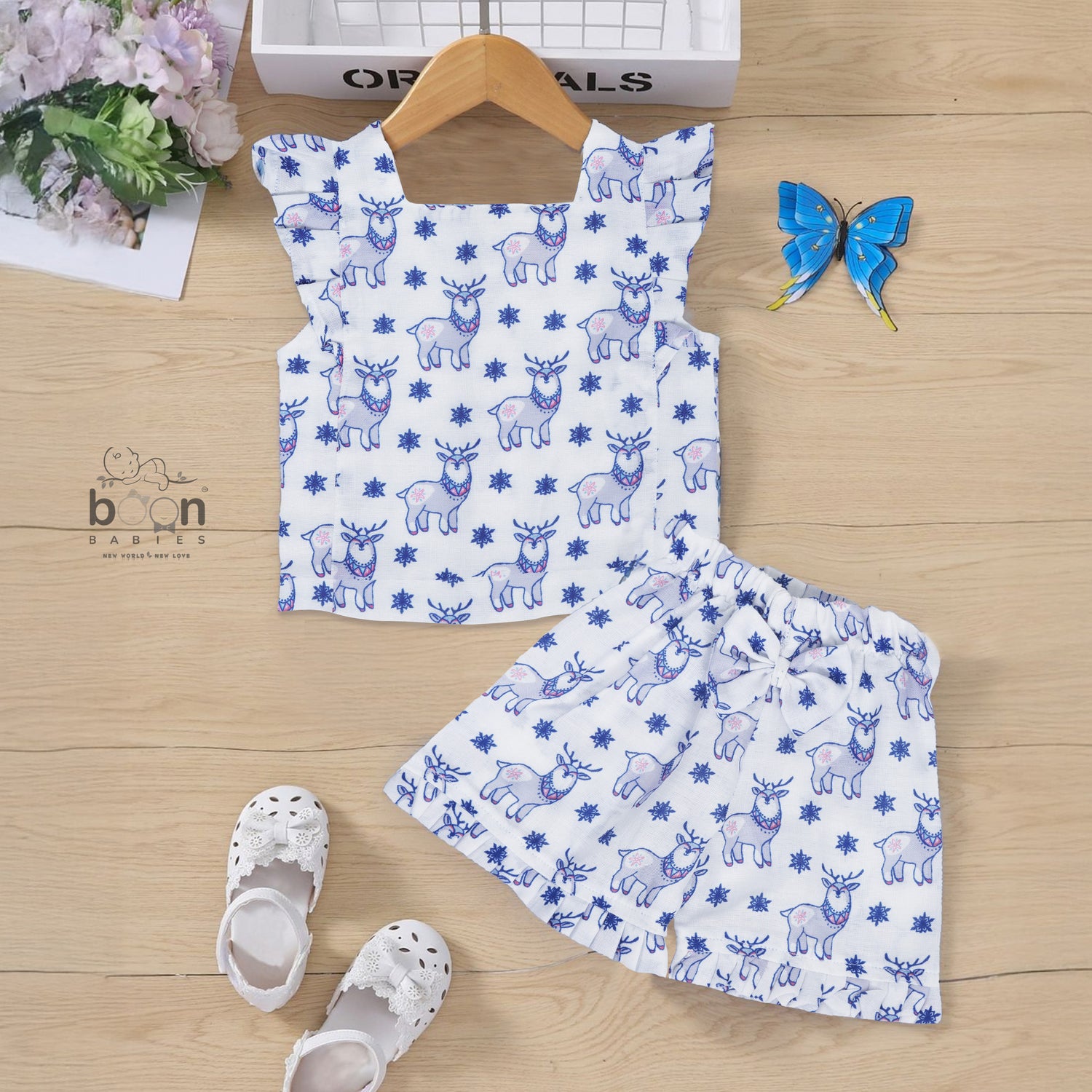 White cotton frill top & shorts set with blue reindeer print. Ages 6M–5Y. Cute, comfy & festive casual wear for baby girls