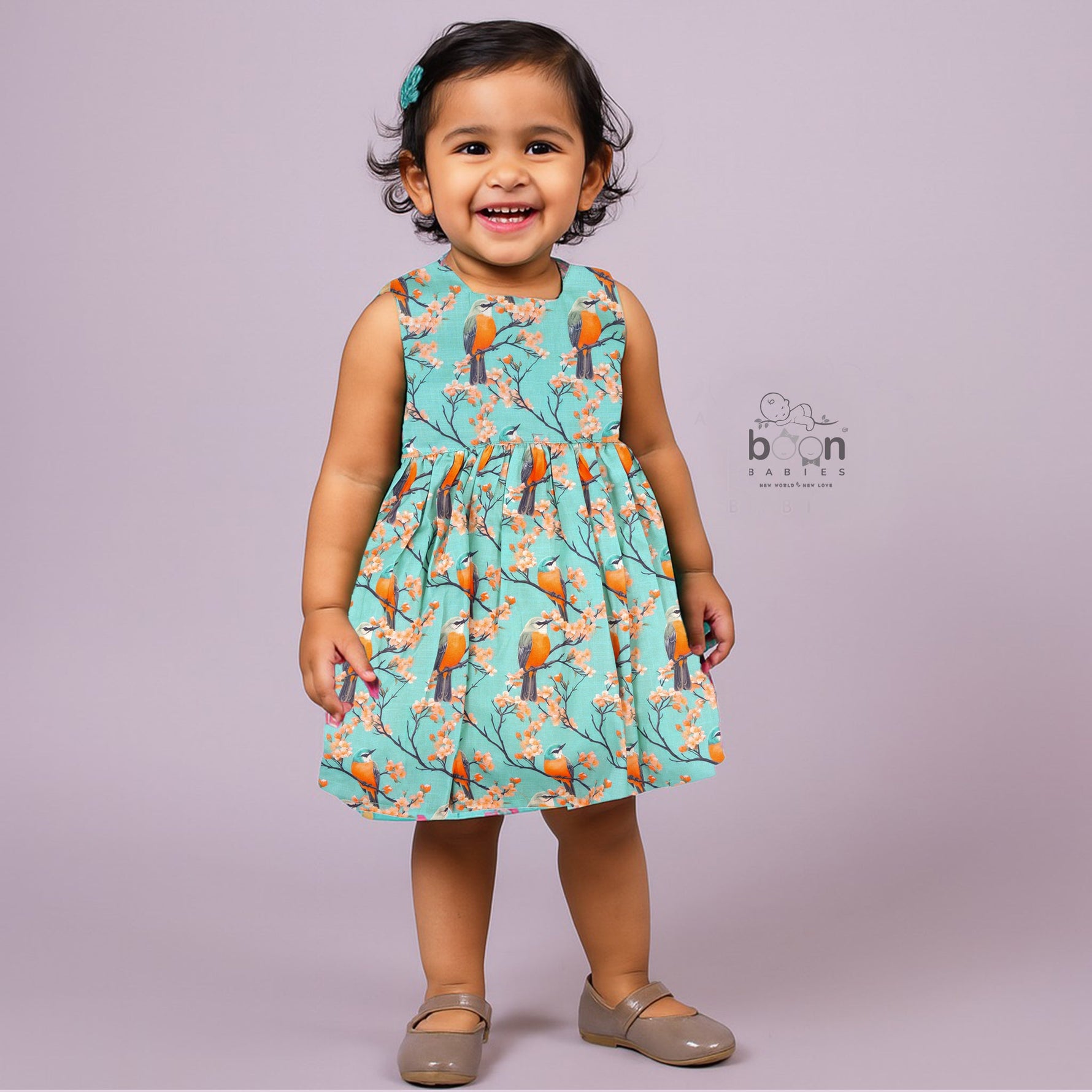 Sleeveless aqua frock with orange birds and peach blossoms printed on soft slub cotton fabric – suitable for girls aged 1 to 4 years from Boon Babies, Coimbatore.