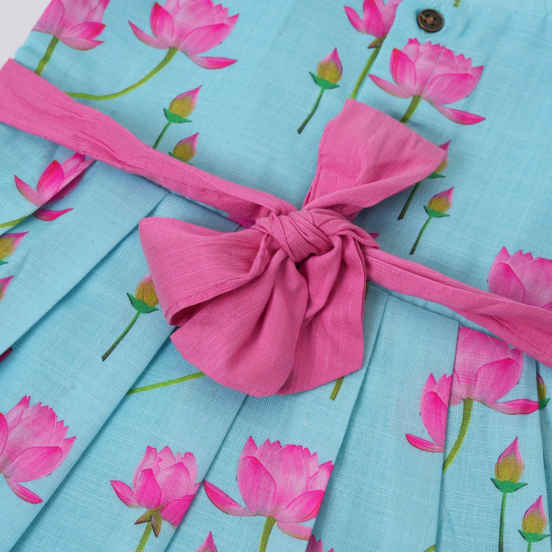 Adorable sleeveless cotton frock with pink lotus prints & bow. Ages 1–4 years. Comfortable, stylish & perfect for festive and casual occasions.