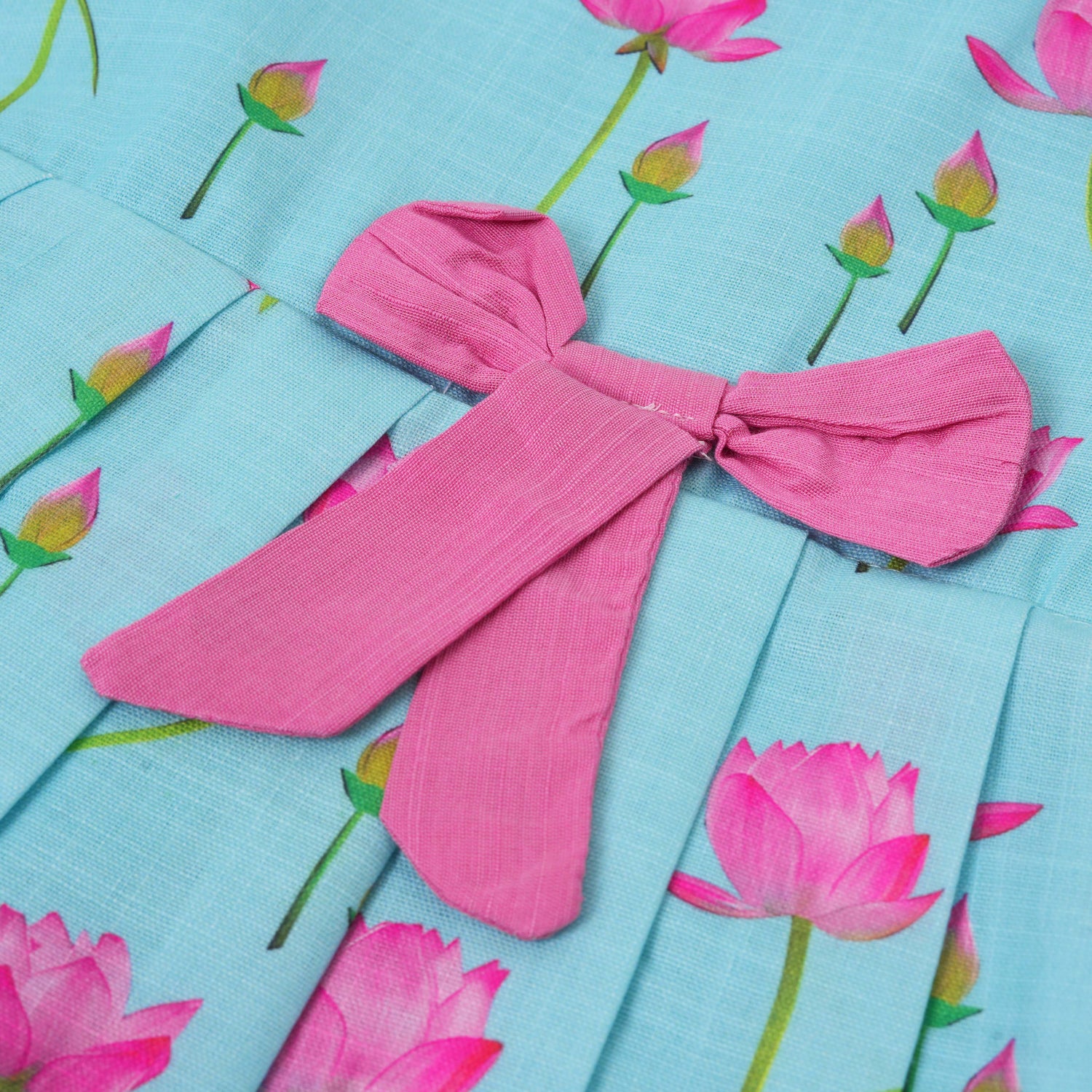 Adorable sleeveless cotton frock with pink lotus prints & bow. Ages 1–4 years. Comfortable, stylish & perfect for festive and casual occasions.