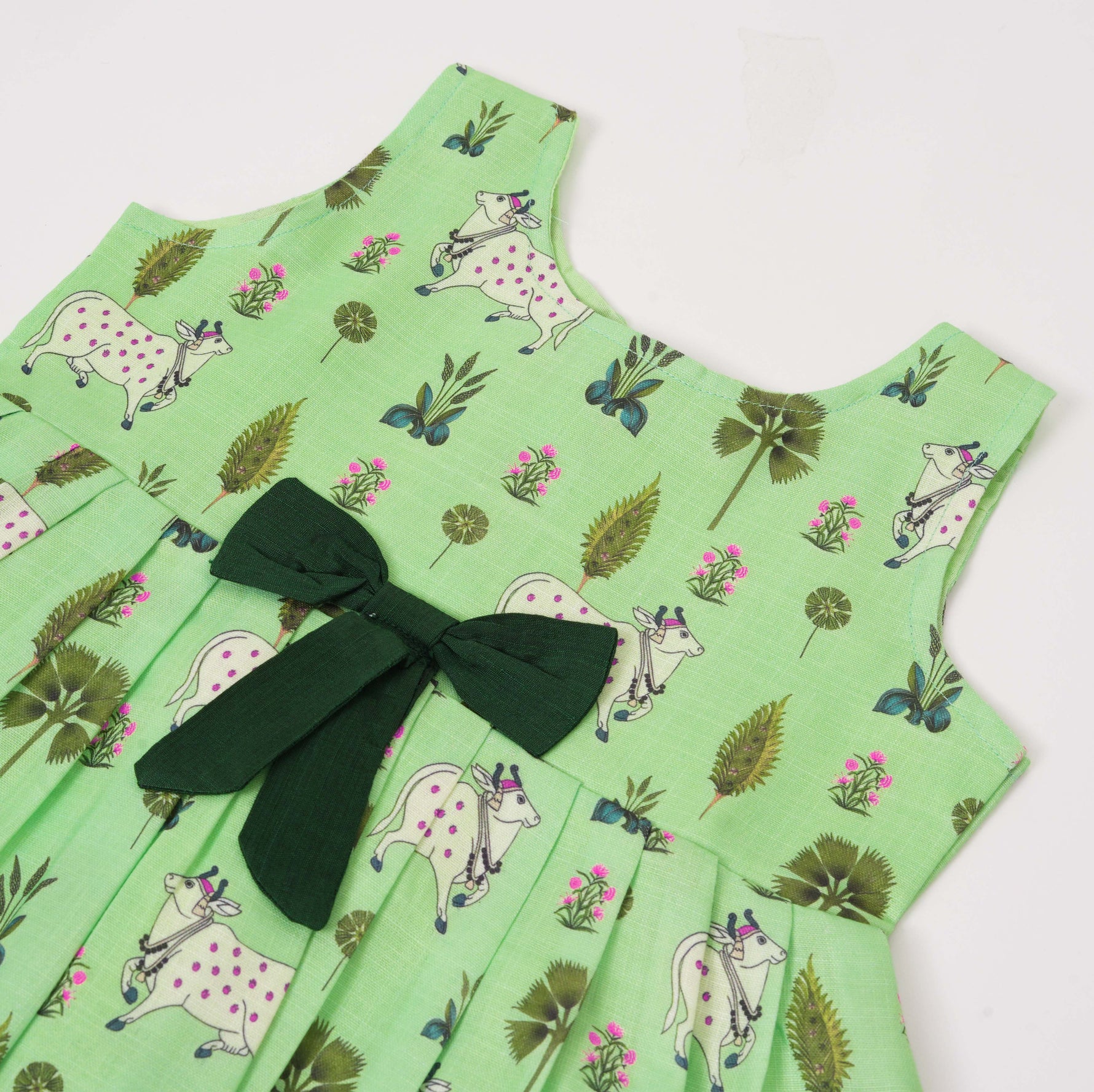 Cute sleeveless cotton frock in green with deer & floral prints. Ages 1–4 years. Soft, breathable & perfect for festive and casual looks.
