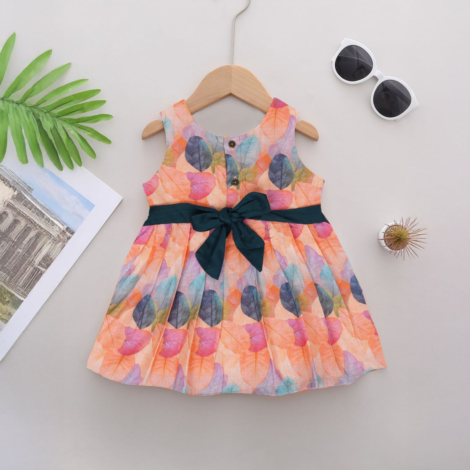 Colorful sleeveless cotton frock with multicolor leaf prints & bow. Ages 1–4 years. Perfect for festive outings, birthdays & everyday cuteness.