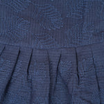 Navy blue sleeveless Hakoba frock for baby girls, featuring soft floral embroidery and pleated cotton design, placed flat on a beige backdrop with heart-shaped decor.