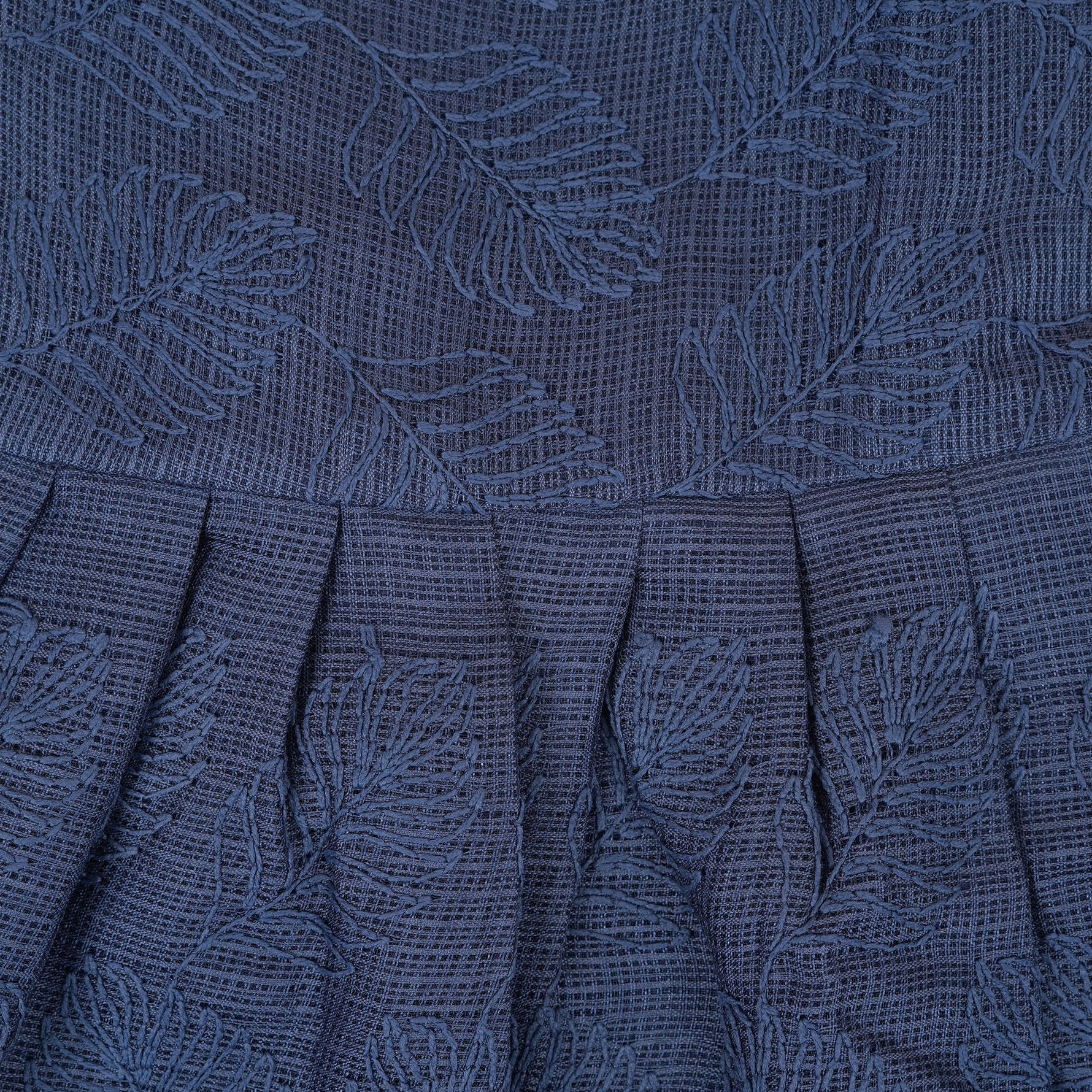 Navy blue sleeveless Hakoba frock for baby girls, featuring soft floral embroidery and pleated cotton design, placed flat on a beige backdrop with heart-shaped decor.