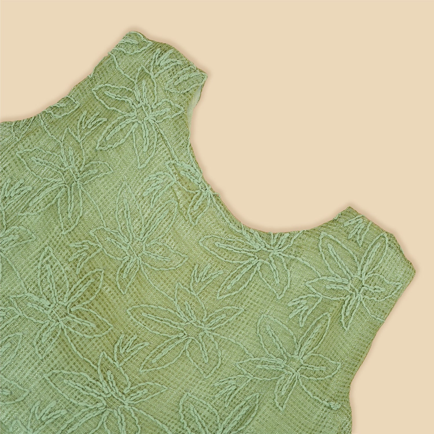 Pastel green sleeveless Hakoba frock for baby girls, featuring floral embroidery and pleated skirt design. Lightweight cotton fabric, displayed flat against a soft beige background with a decorative heart and flowers.