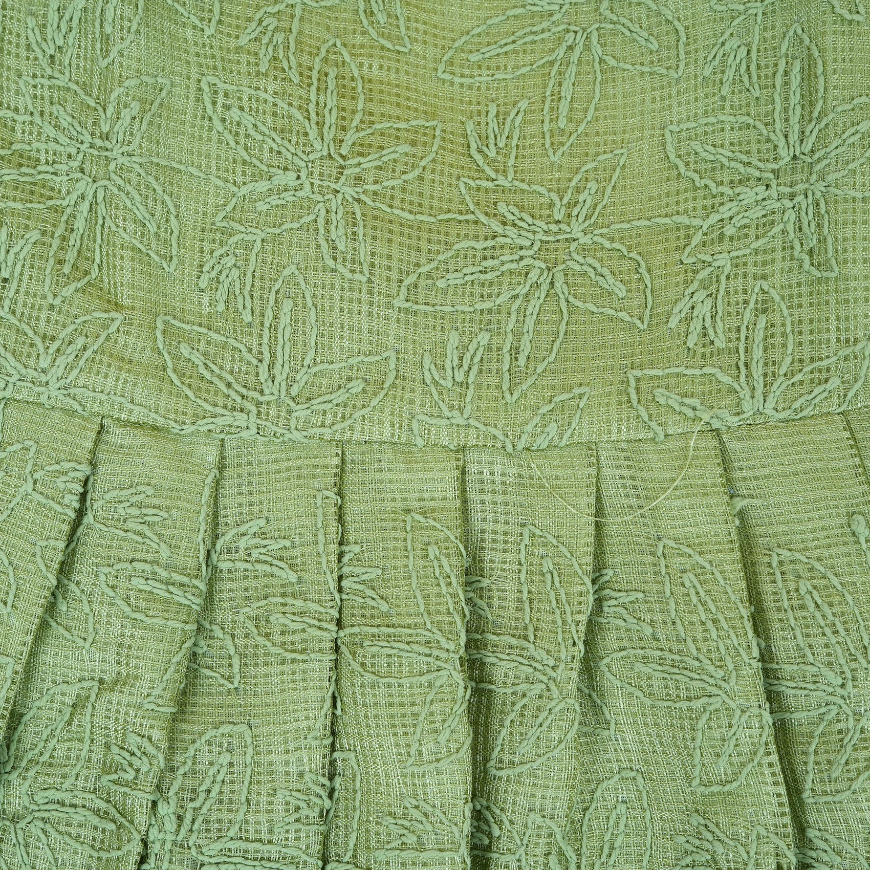 Pastel green sleeveless Hakoba frock for baby girls, featuring floral embroidery and pleated skirt design. Lightweight cotton fabric, displayed flat against a soft beige background with a decorative heart and flowers.