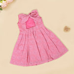 Pink sleeveless Hakoba frock for baby girls, featuring floral embroidery and pleated skirt design, laid flat on a beige background with soft floral props.