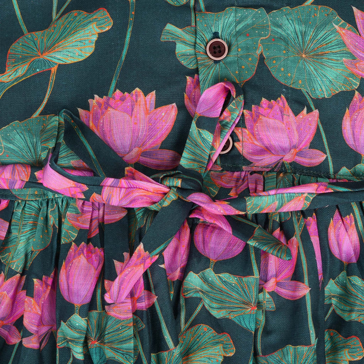 Sleeveless dark green frock for girls aged 1 to 4 years, featuring pink lotus floral print in slub cotton – from Boon Babies, Coimbatore.