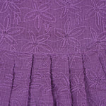 Orchid purple Hakoba frock for baby girls, sleeveless with floral embroidery and pleated skirt, displayed flat on beige background with soft props.