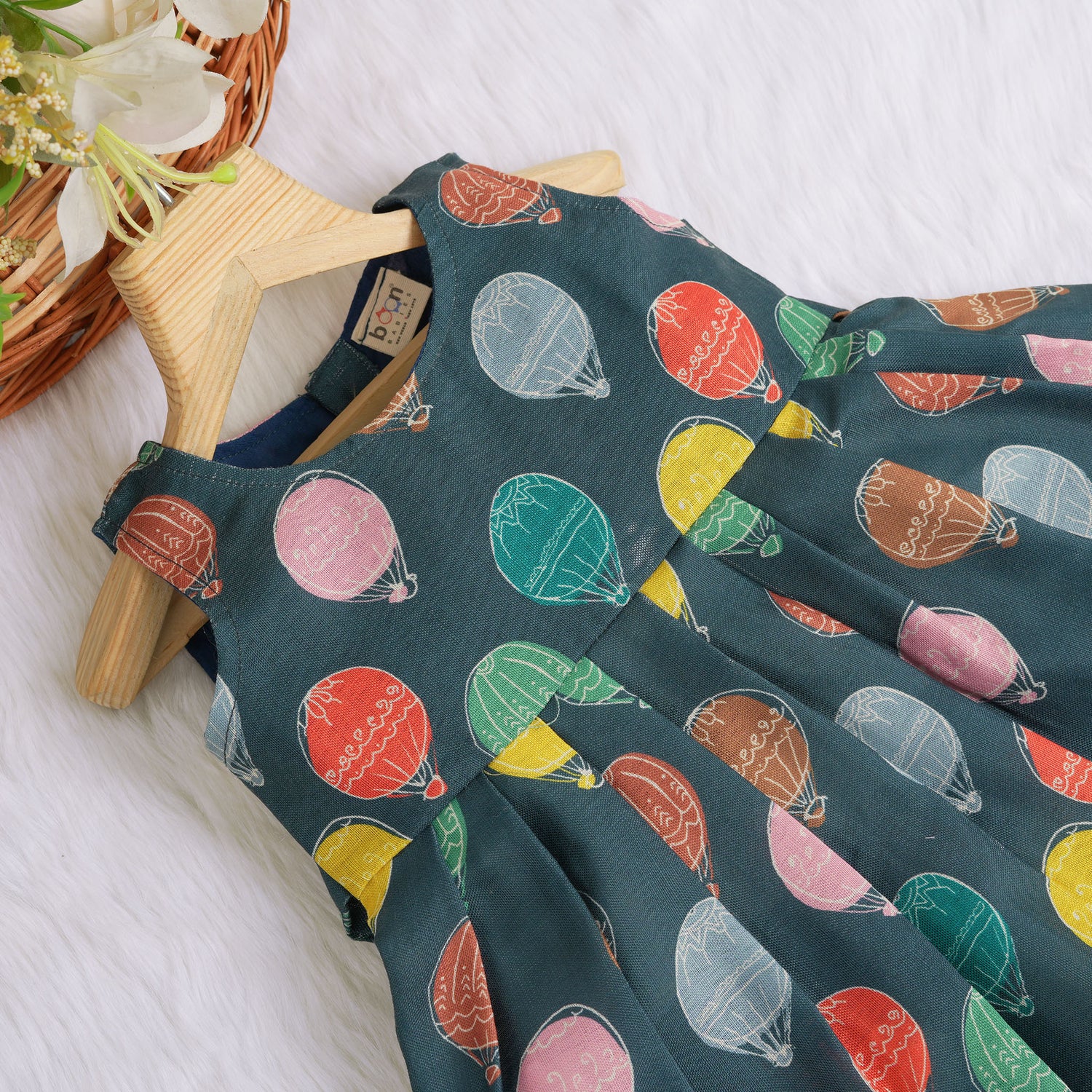 Little girl in a sleeveless denim blue frock with colorful balloon prints, made of slub cotton – part of Boon Babies babywear collection in Coimbatore.