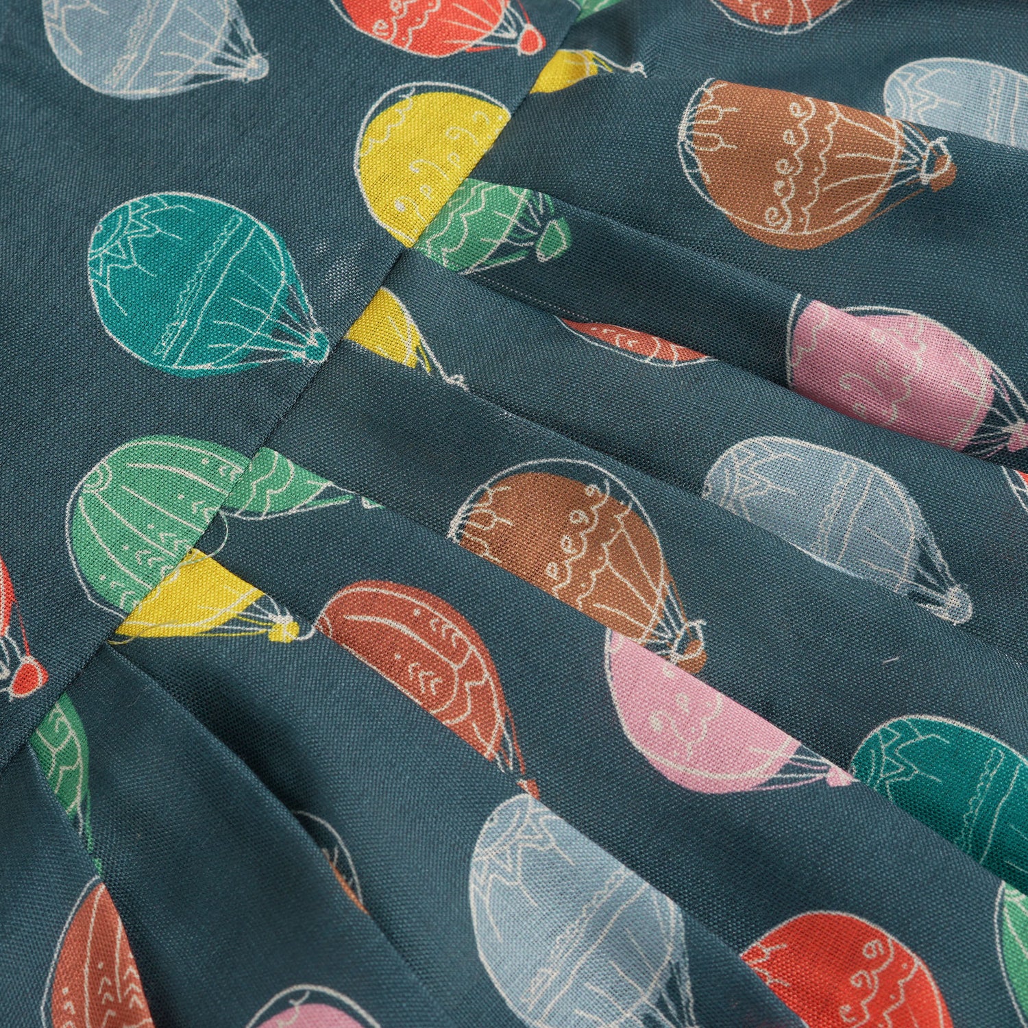 Little girl in a sleeveless denim blue frock with colorful balloon prints, made of slub cotton – part of Boon Babies babywear collection in Coimbatore.