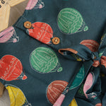 Little girl in a sleeveless denim blue frock with colorful balloon prints, made of slub cotton – part of Boon Babies babywear collection in Coimbatore.