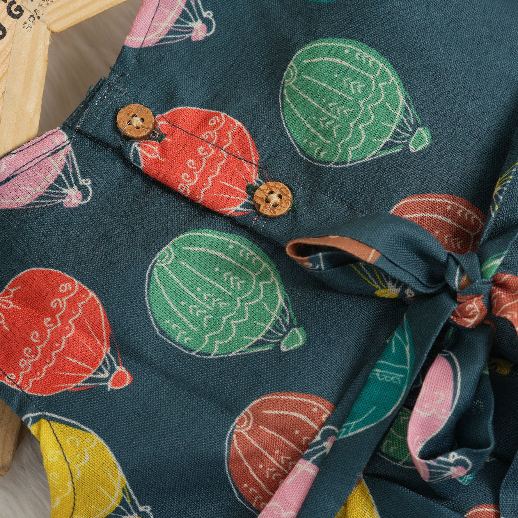 Little girl in a sleeveless denim blue frock with colorful balloon prints, made of slub cotton – part of Boon Babies babywear collection in Coimbatore.