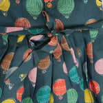 Little girl in a sleeveless denim blue frock with colorful balloon prints, made of slub cotton – part of Boon Babies babywear collection in Coimbatore.