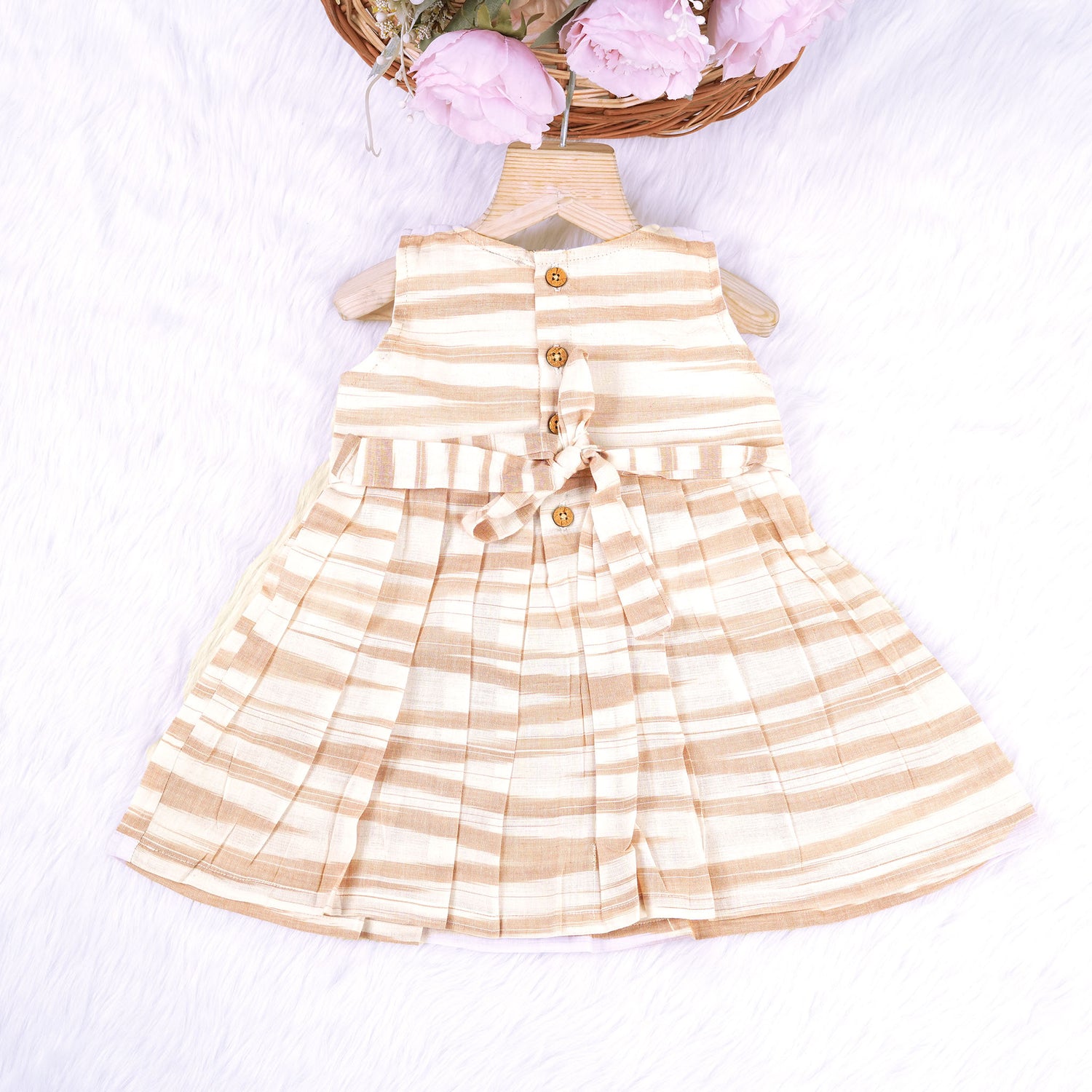 Smiling young girl wearing a sleeveless beige and white striped cotton frock from Boon Babies’ kidswear collection in Coimbatore – perfect for ages 6 months to 5 years.